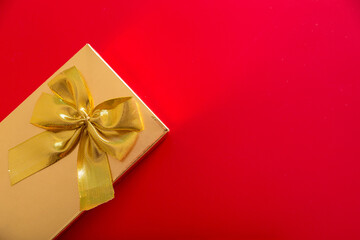Gift in a golden package with a bow on a red background