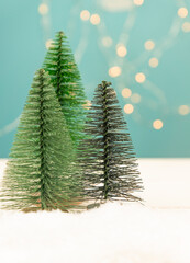 Miniature toy Christmas trees on a wooden table with snow. Imitation realistic scene. Banner