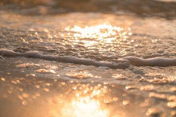 bubbles at the top of the wave on the beach with the sunset sky