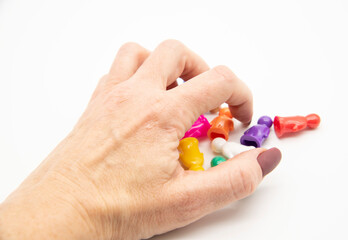 Women's hand with a manicure rakes in a bunch of little plastic figurines of humans.
