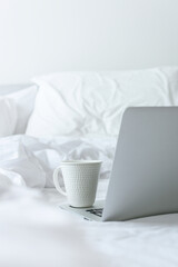 Cup of coffee on the computer on white bed