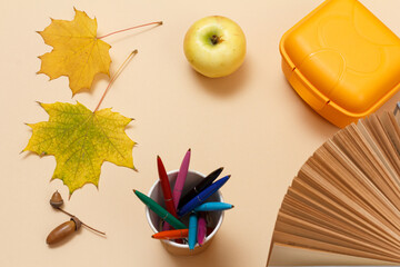 Ripe apple, lunchbox and dry leaves on a beige background, Top view.