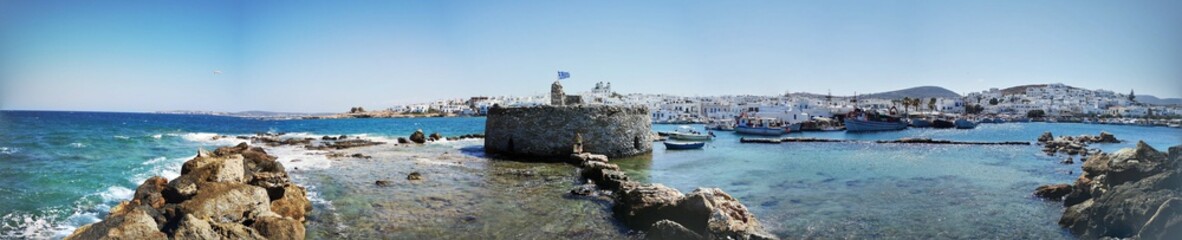 beautiful panorama of the village of Naousa with coast, fort and traditional historical white Greek buildings on the island of Paros, Greece