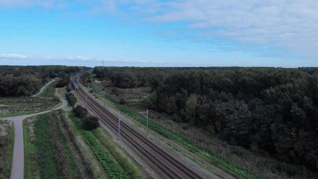 Dutch train passing on a railway track on a summer day in the netherlands, Drone shot