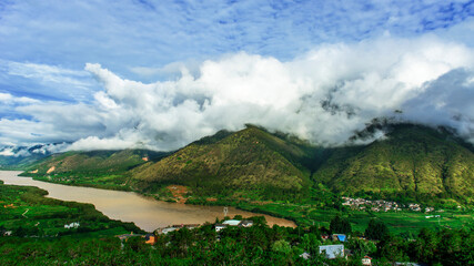 Fototapeta na wymiar The river on the mountain, the white clouds on the top of the mountain, the beautiful natural scenery