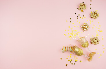 Golden ribbons, bows and confetti lie on a pink background. Copy space