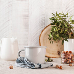 A metal mug on a linen tablecloth, a white jug of milk on the back. Still life in rustic style. Copy space.