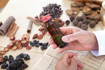 Chinese medicine doctor holding a bottle of medicine in his hand view on the table covered with Chinese medicine