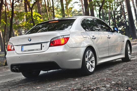 Chernihiv, Ukraine - July 6, 2018: BMW E60 on the forest road. A car with lights on in the forest