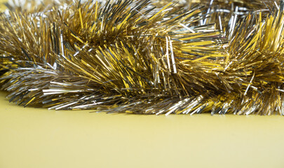 Golden and silver  tinsel, Christmas ornament on yellow background background..