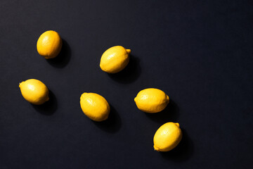 Fototapeta na wymiar Fresh lemons pattern on black background. Copy space. Top view. Flat lay. Citrus fruits. Vitamins for health. Liposomal vitamin C. Immune system booster. Lemon for vegan, vegetarian alkaline diet