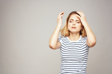 Fototapeta premium A woman in a striped T-shirt holds her hands in front of her emotions displeasure light background