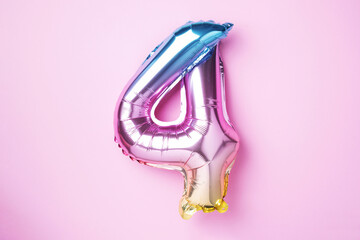 Creative layout. Rainbow foil balloon number and digit four 4. Birthday greeting card. Anniversary concept. Top view. Copy space. Stylish colored numeral over pink background. Numerical digit.