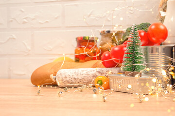 Christmas donations - food donations on light background with copyspace - pasta, fresh vegatables, canned food, baguette, cooking oil with Christmas decorations. Food bank, food delivery concept