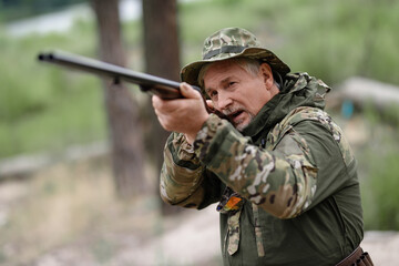 Old Sniper Hunter Taking Aim with Rifle in Forest.