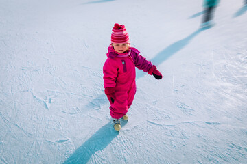 Fototapeta na wymiar happy little girl learning to skate in winter