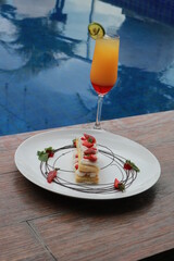 Strawberry Mille Feuille cake in white plate with fresh fruit punch.