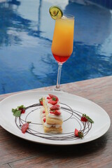 Strawberry Mille Feuille cake in white plate with fresh fruit punch.