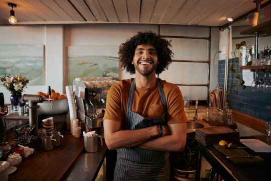 Portrait of confident male barista standing with arms crossed at coffee house