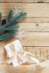 Christmas background with gift, spruce branch, pine cone and decor on wooden boards, top view. Christmas card concept with free space. Background for Merry Christmas and Happy New Year greetings.