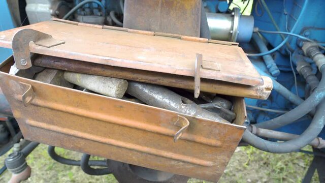An old tool box on the side of the vintage bus being abandoned on the abandoned parking lot