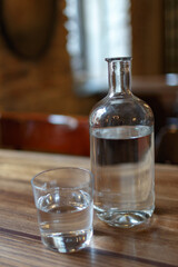 glass bottle with water and a glass on a wooden table. Vintage interior