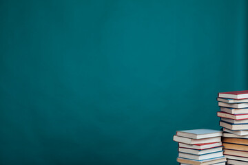 many stacks of educational books for exams in the library on the green background of the university