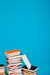 many stacks of educational books for exams in the library on a blue background
