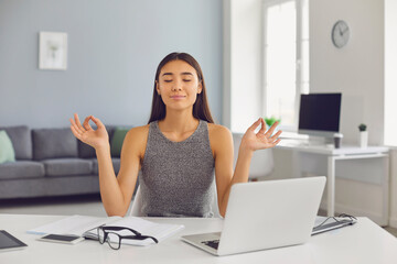 Calm business lady meditates with her eyes closed in her office during a break.