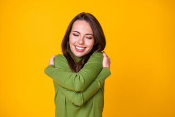 Close-up portrait of pretty glad dreamy cheerful girl hugging herself rest isolated over bright yellow color background