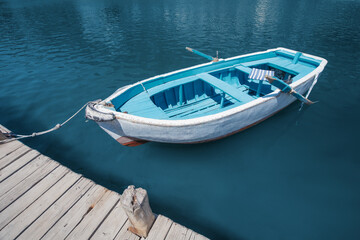 An old wooden fishing boat is moored to the pier