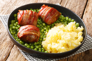 Faggots meatballs with a garnish of green peas and mashed potatoes close-up in a plate on the table. horizontal