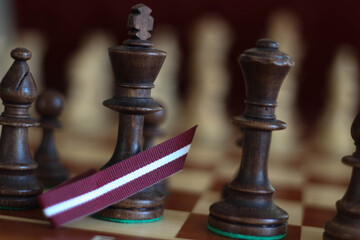 Fototapeta premium Chess pieces on a Board Game. Latvia. Decoration. White and red. Latvia. Colors of Flag. Latvian flag top view.
