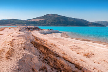 Panoramic view of the white sandy beach with grass bushes on the famous lake Salda in Turkey. Wonders of nature and turkish maldives concept