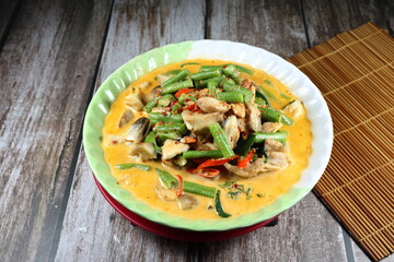 Spicy Thai curry soup of cutting fresh bean, mushroom and chicken seasoning with coconut milk and chilly paste in the bowl. Famous traditional menu in Asia restaurant. 