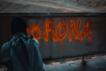 Hidden man writes Corona on a abandoned wall with spray paint