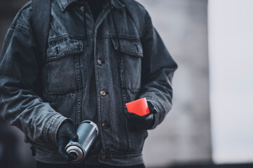 No face photo of graffitist in denim coat with spray paint can 