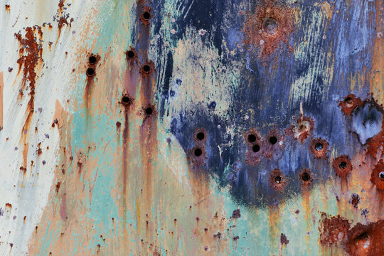Abstract grunge metal texture. Brown metal surface with rust and bullet holes. Wallpaper with bullet holes for design. Weathered metal wall. Metal door with corrosion and rust.