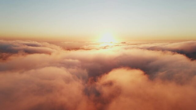 Moving white clouds blue sky scenic aerial view sunset golden sun summer. Drone flies high back in blue sky through fluffy clouds in evening. Sun is hidden behind clouds at fog. Relax. Nature