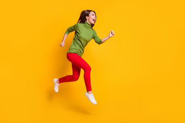 Fototapeta na wymiar Lady jump up rushing excited wear casual green pullover shoes red trousers isolated yellow color background