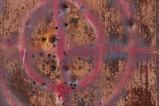 Rusty metal wall with through holes and a hunting target painted in paint