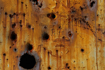 Orange textured metal surface with holes close-up. Damaged metal with rust and bullet holes. Old...
