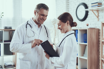 Two doctors look at the notebook and smile. 