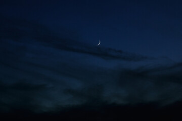 Sickle of the moon in the dark evening clouds. Night photo with the moon and clouds. Moonlight and...