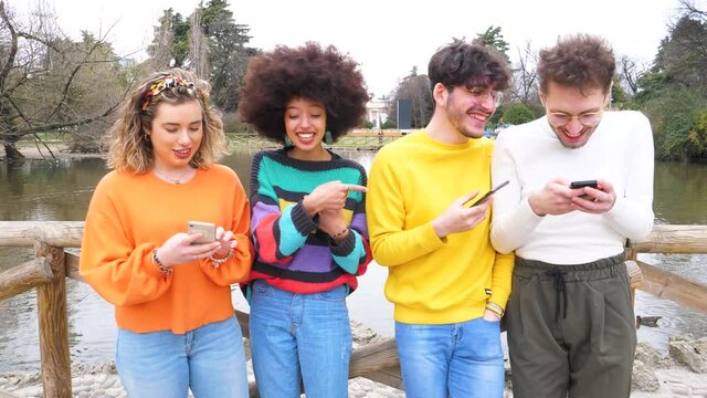 Group of multiethnic young friends millennials using mobile phones addicted to technology trends following and chatting  on social media