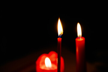 3 red ritual candles on dark isolated background. Burning church candles for design, Photoshop overlay and website. Glowing romantic flames on candles in complete darkness. Best romantic candles
