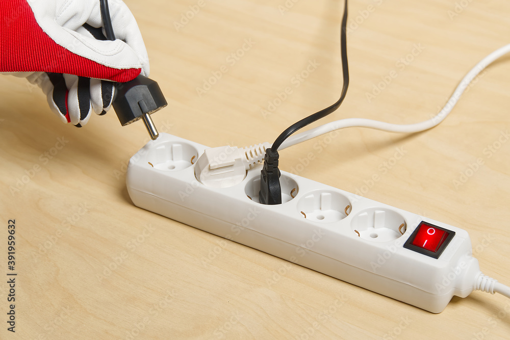 Poster closeup of an electrician plugging extension cords into each other. mans hand plugging extension cor