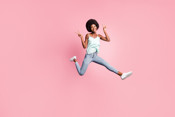 Full size portrait of excited person jump show v-sign wear jeans singlet sneakers isolated on pink...