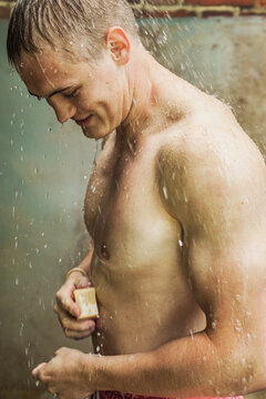 Young man with soap showering outdoors
