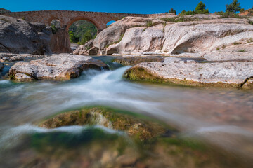 beautiful river between rocks with a stone bridge in the background